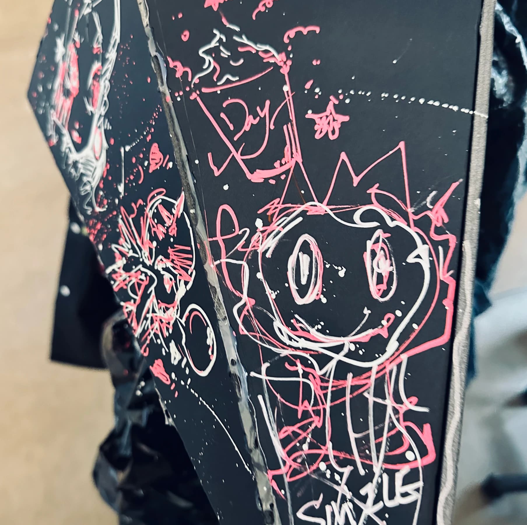 White and pink character drawings on a black surface.