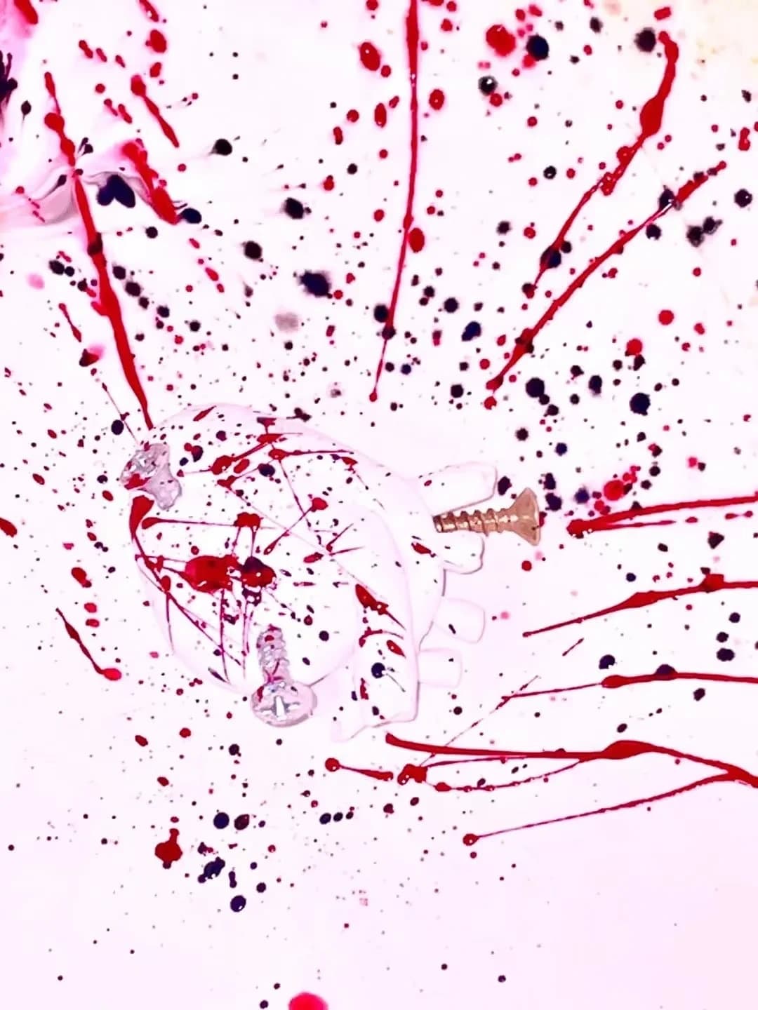 Red and black splatter marks on a white surface.