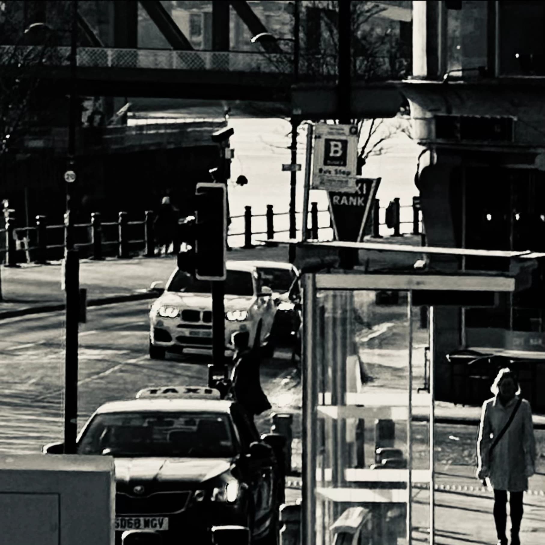 Black-and-white street scene with vehicles and pedestrians.
