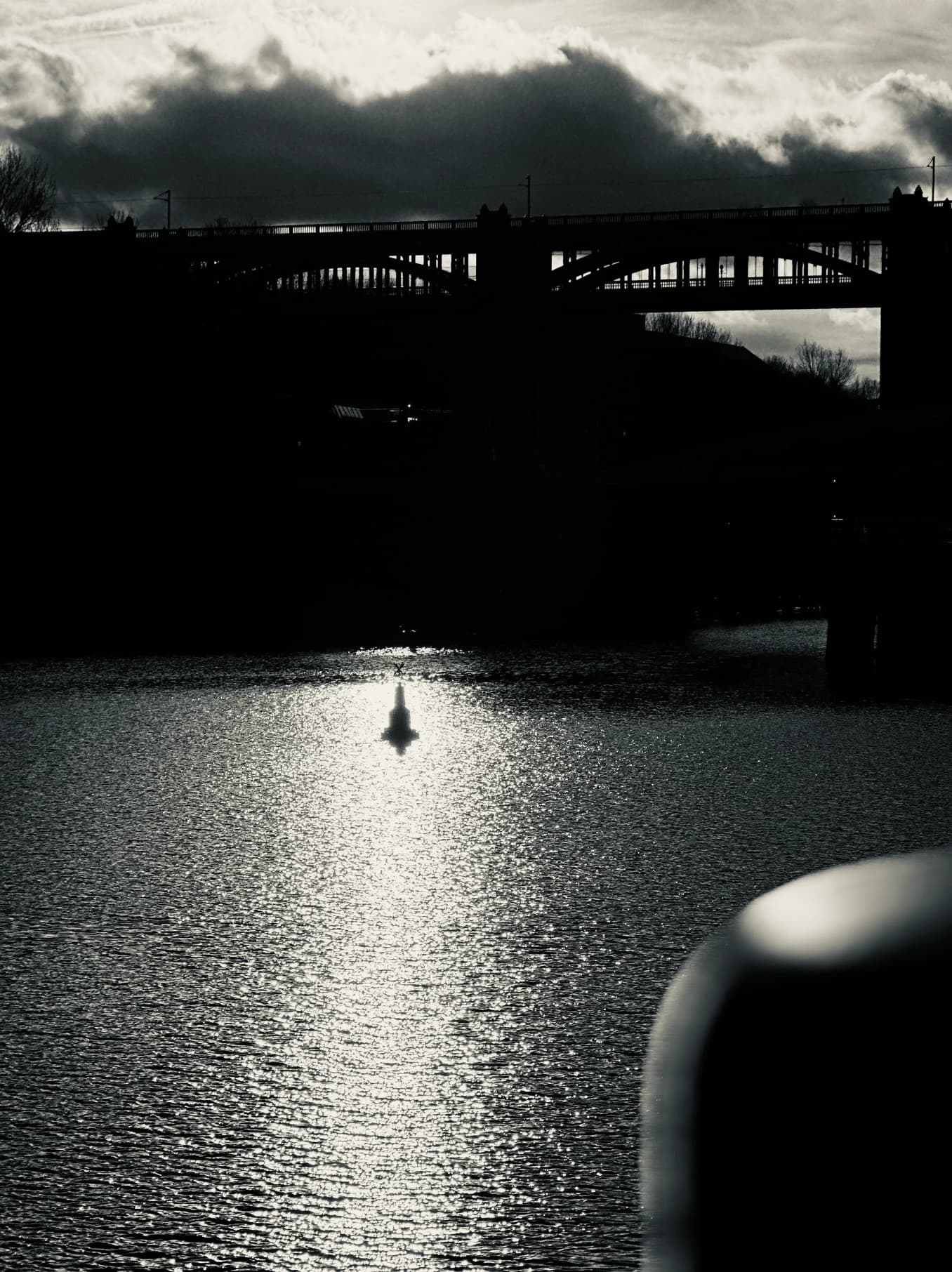 Black-and-white view across water under a clouded sky.