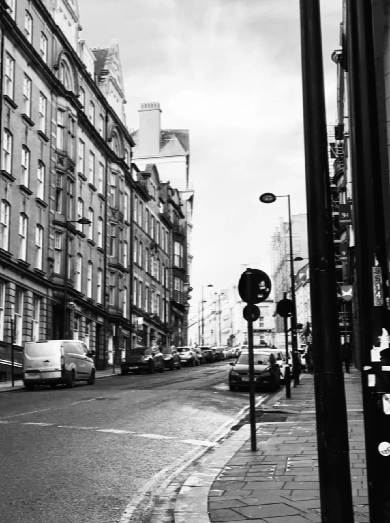 Black-and-white view along a street between tall buildings.