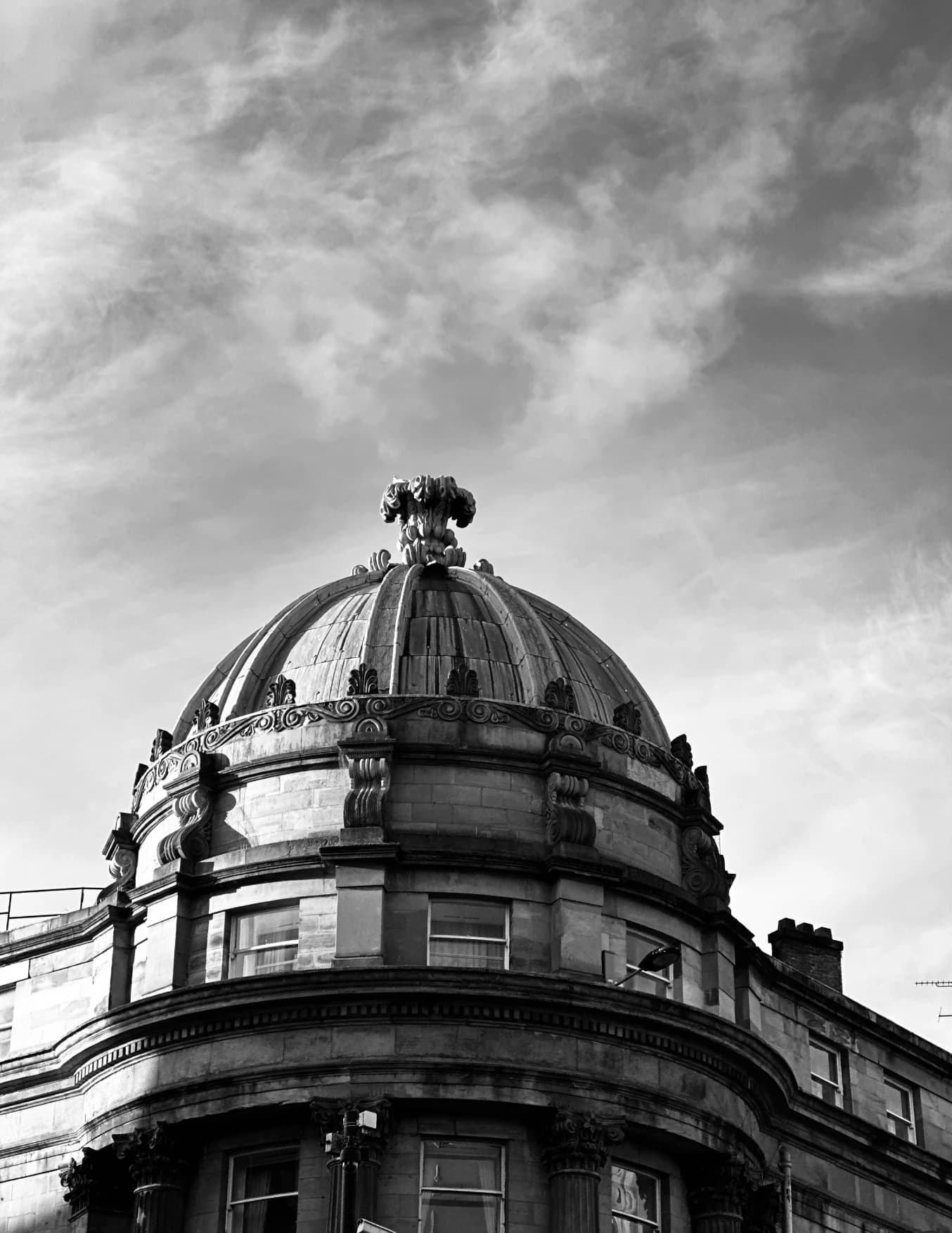 Domed building against a cloudy sky in black and white.