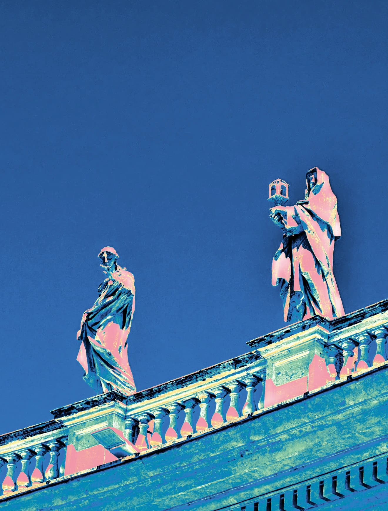 Two rooftop statues against a deep blue sky.