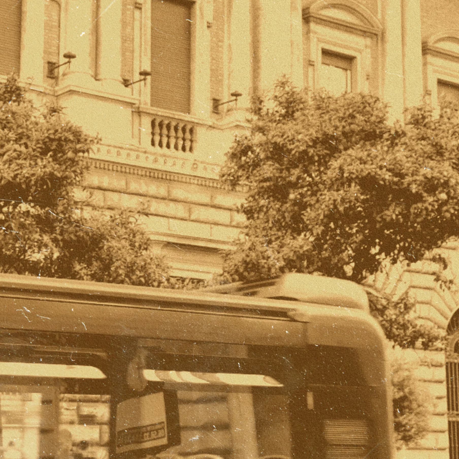 Sepia street scene with a bus and trees.