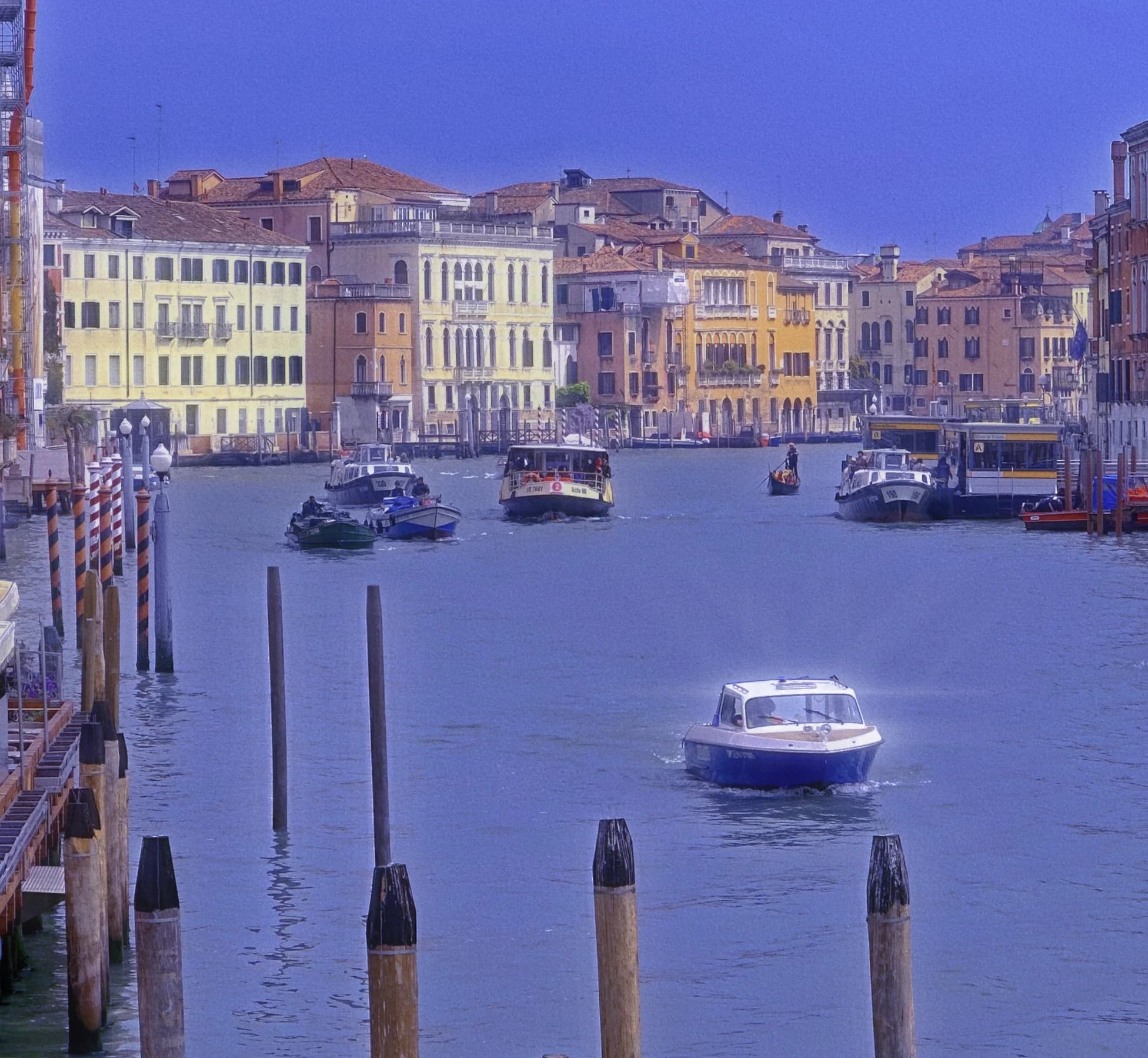 Blue-toned canal scene with buildings and boats.