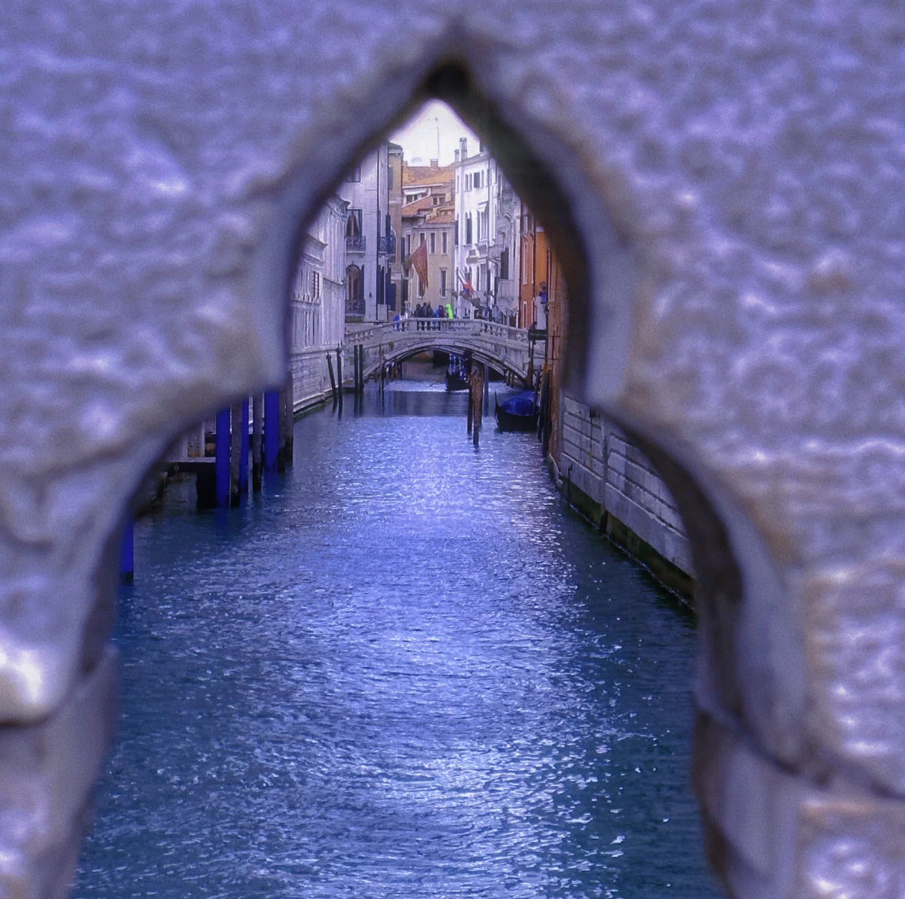 Canal seen through a pointed opening in a stone wall.